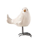 White ceramic bird figurine on a black stand against a white background