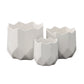 A set of three white ceramic round pots with a matte finish and a geometric design