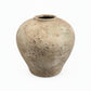 A rustic, textured ceramic vase with a rounded bulbous body and a short, slightly tapered neck, shown on a plain white background.