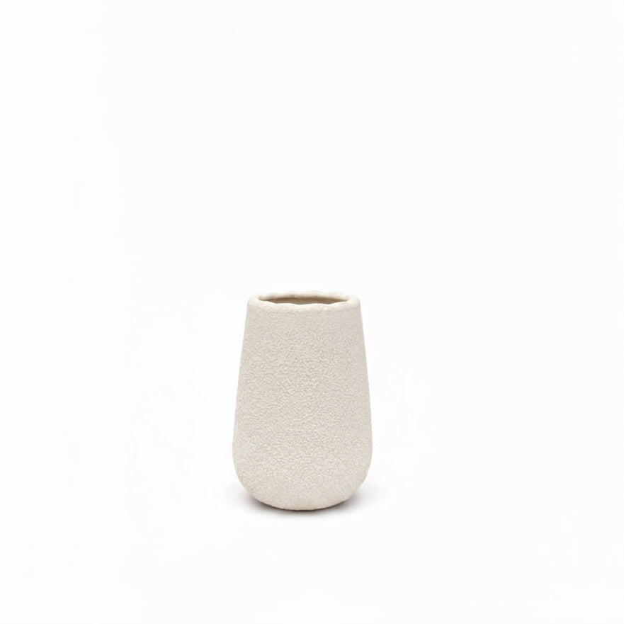 A small, textured ceramic vase in a warm off-white or cream color, photographed against a seamless white background.