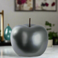 Gray apple-shaped object on a surface with a blurred background