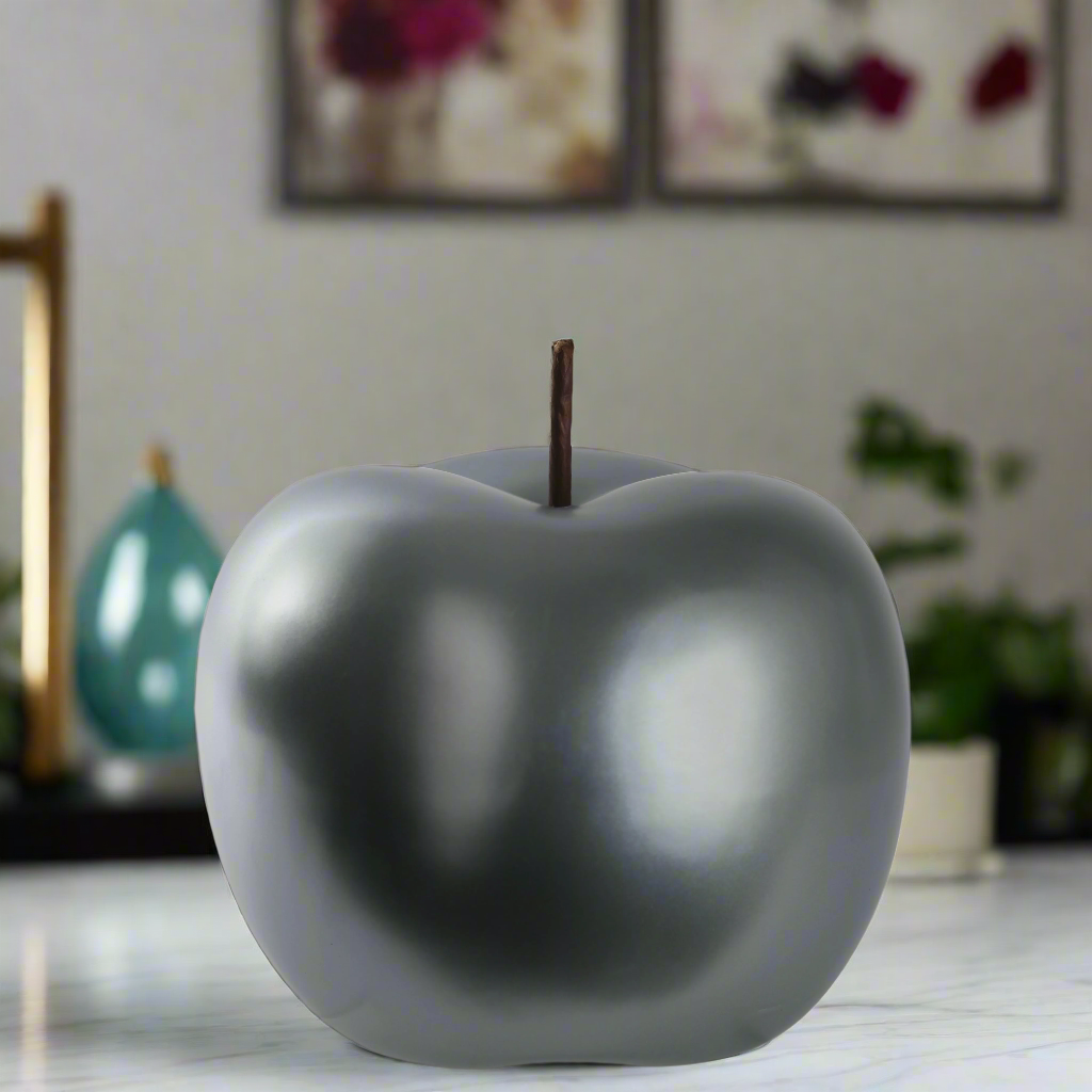 Gray apple-shaped object on a surface with a blurred background