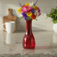 Red vase with colorful flowers on a kitchen counter